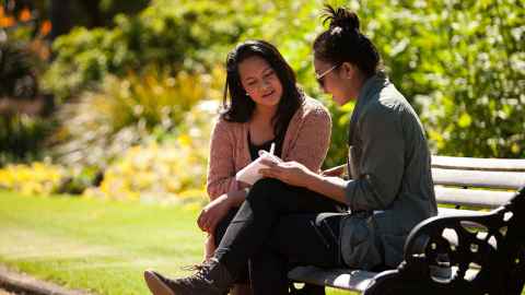 two women talking on a park bench